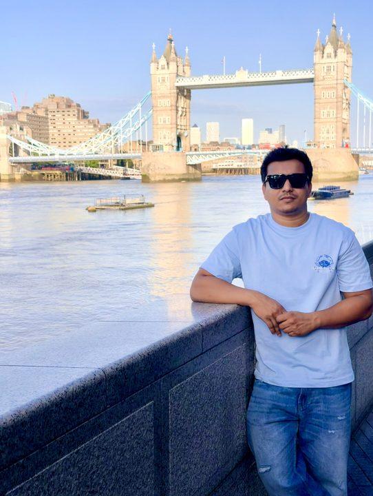 Leaning on a riverside wall in front of Tower Bridge, London