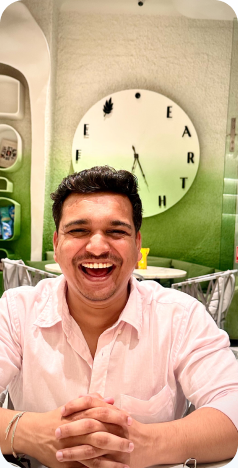 Laughing at a cafe table in front of a wall clock